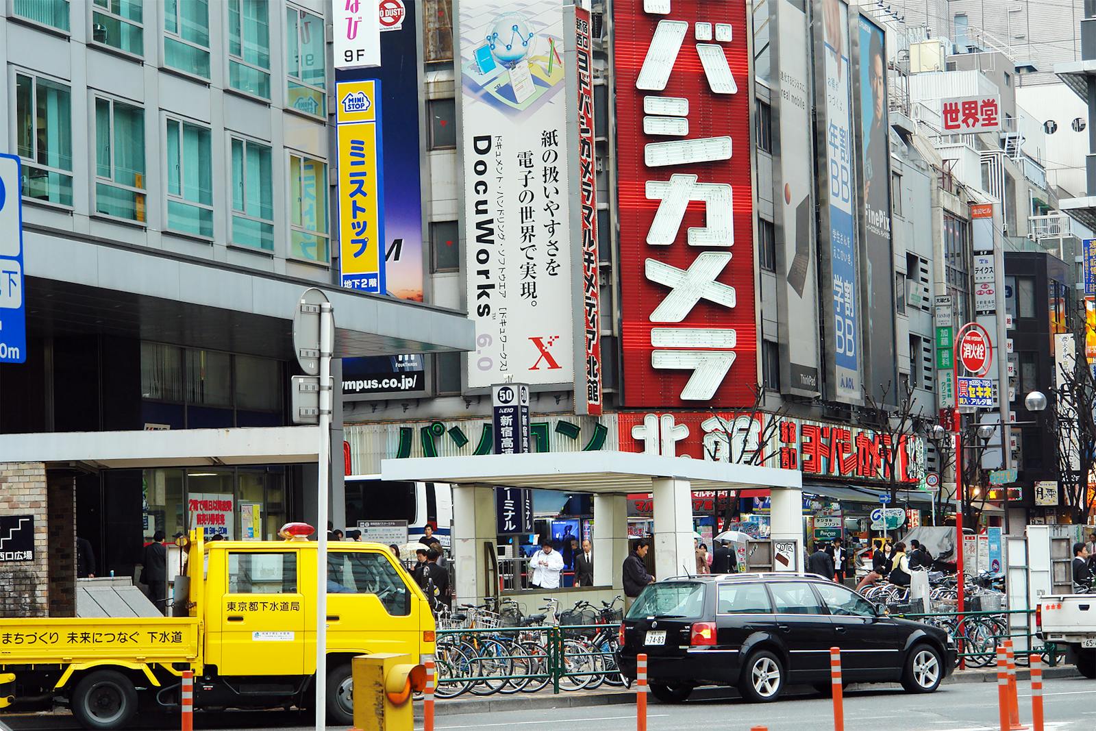 Bustling Shinjuku street in Tokyo at night with colorful neon signs and crowds of people