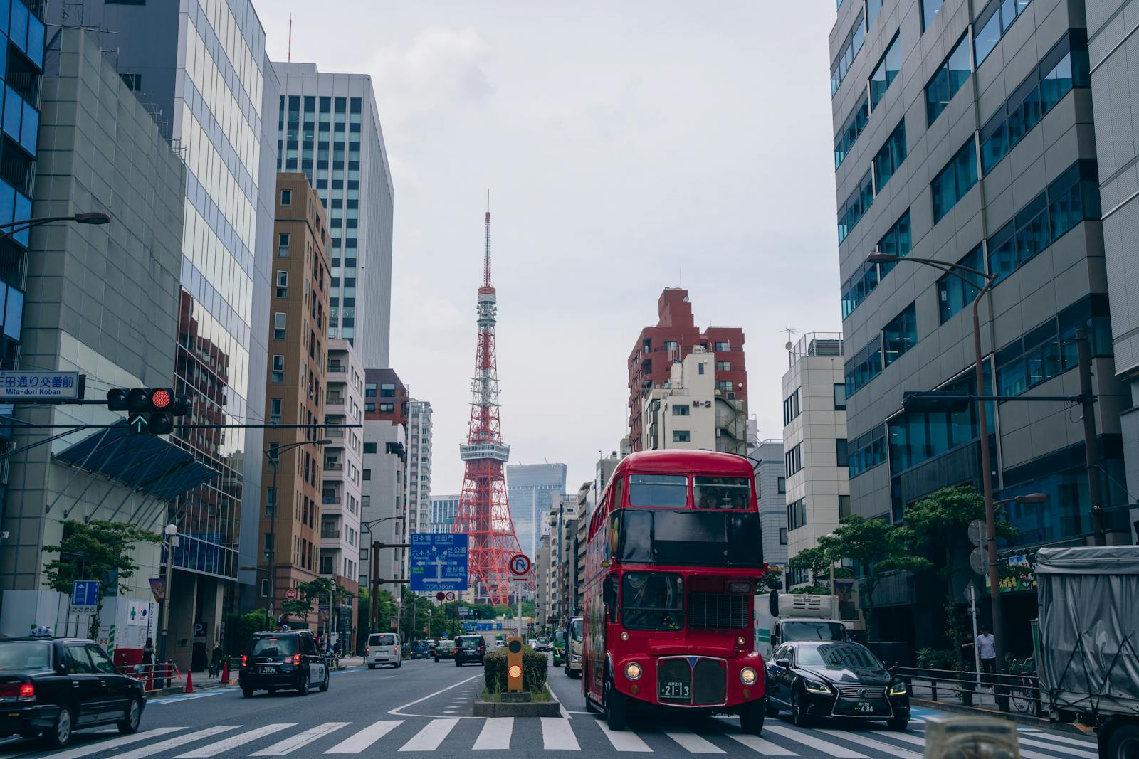 Red double-decker sightseeing bus near Tokyo Tower on a city street