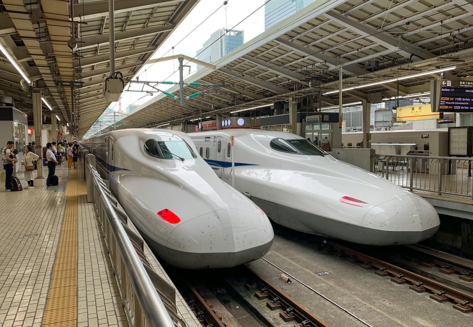Two sleek white Shinkansen bullet trains parked at Tokyo Station platform