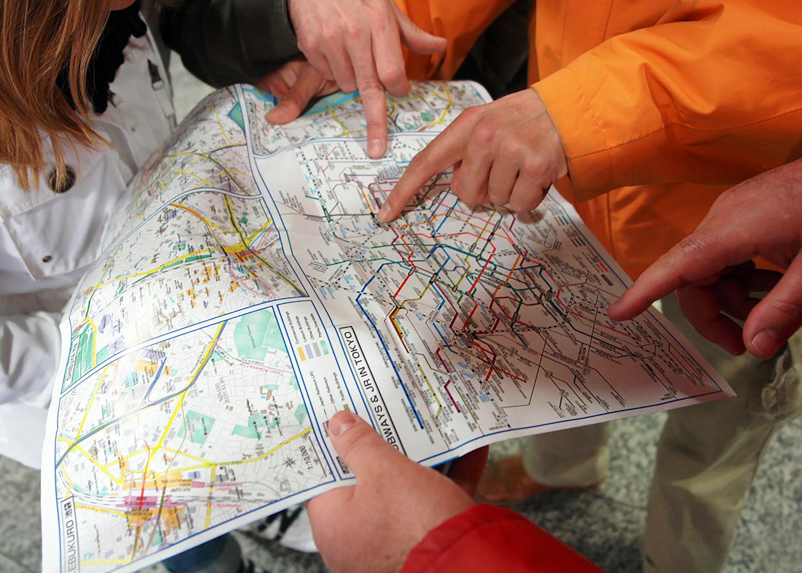 Tourists studying a Tokyo subway map to plan their route through the city