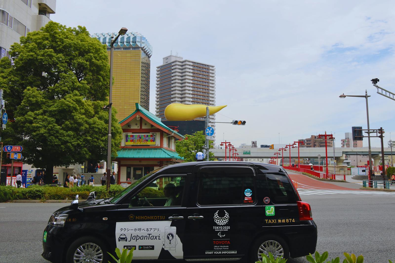 Black Tokyo taxi driving through a city street with urban architecture in the background
