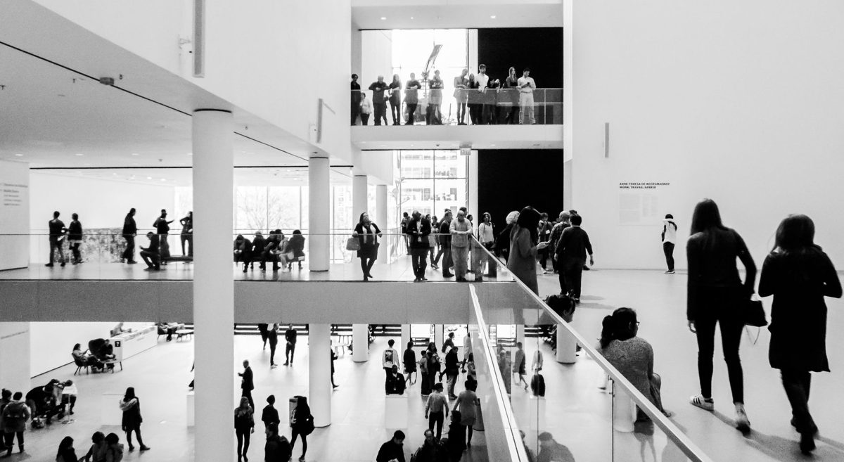 Visitors looking at paintings in a bright museum gallery