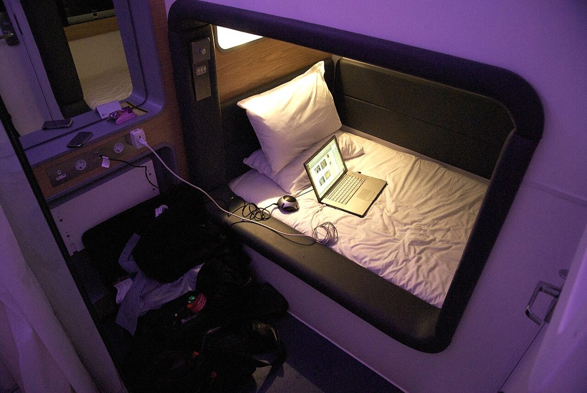 Inside a single capsule hotel pod with mattress, light and power outlet