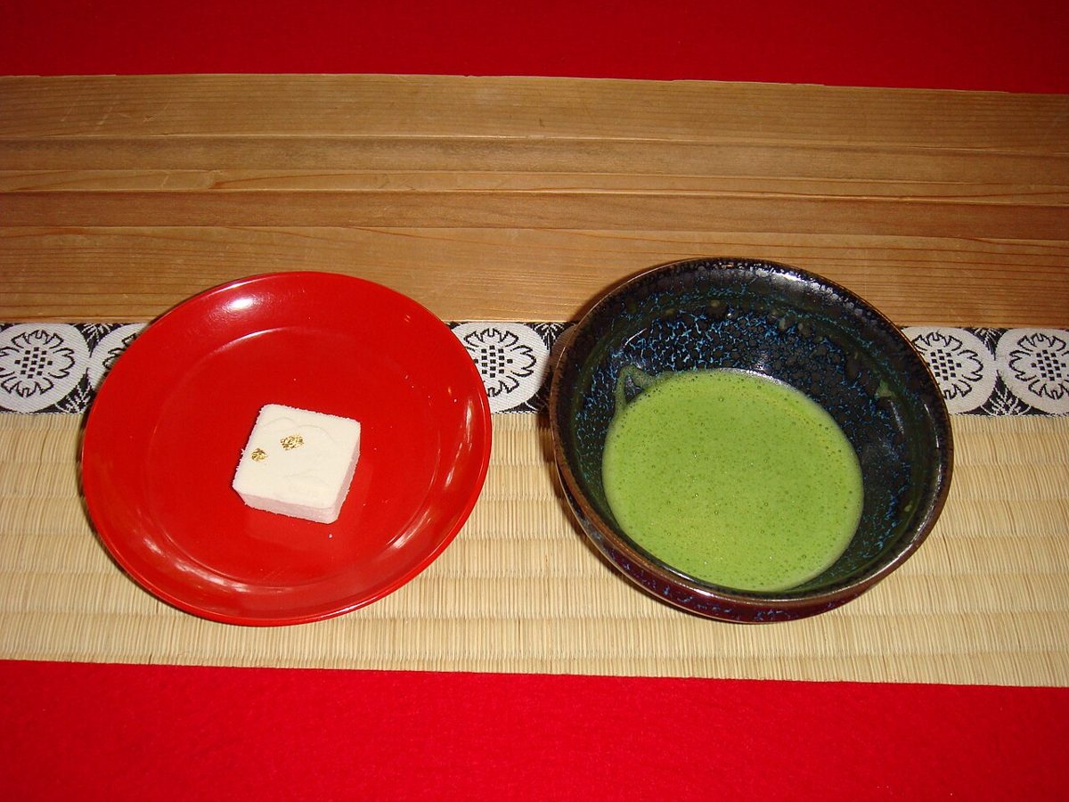 A bowl of matcha served with a seasonal wagashi sweet on a plate
