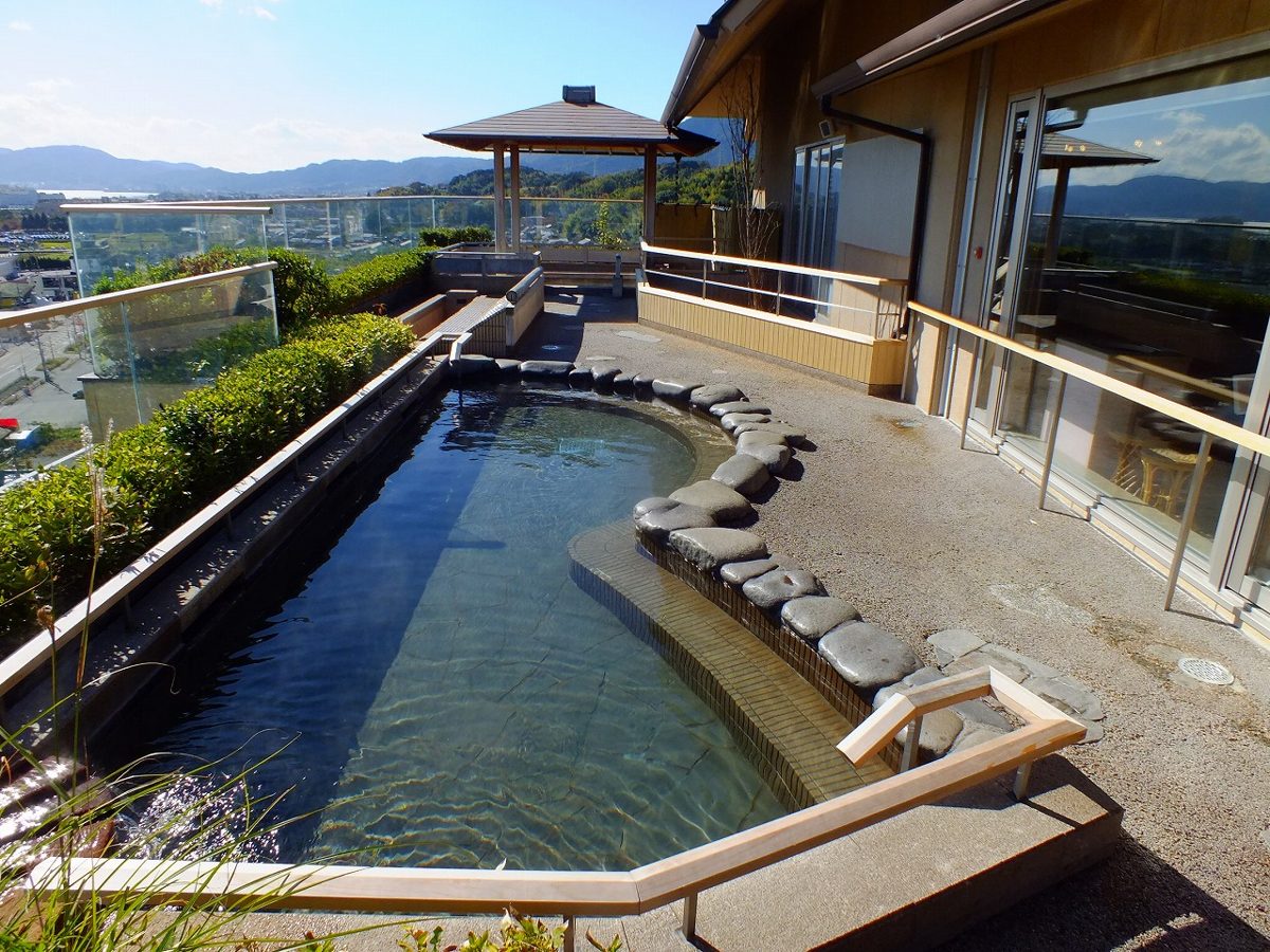 Steaming rotenburo outdoor onsen bath surrounded by rocks and forest in Japan