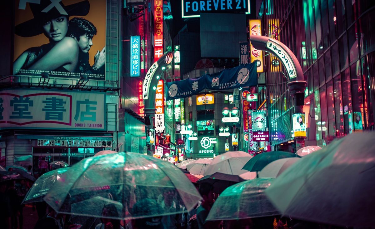 Umbrellas and neon reflections at Shibuya Crossing in the rain