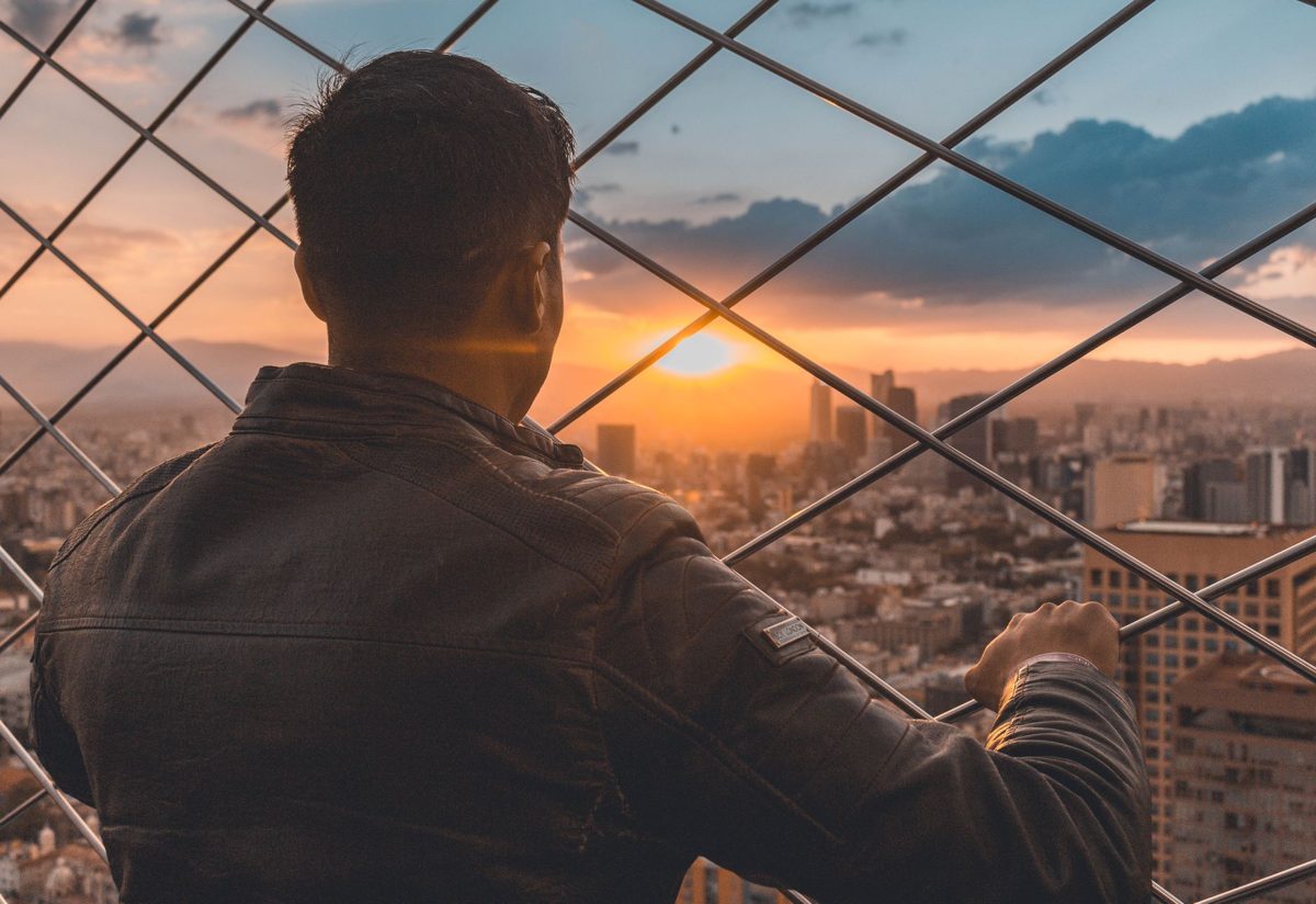 People on an open-air rooftop observation deck looking over Tokyo at sunset