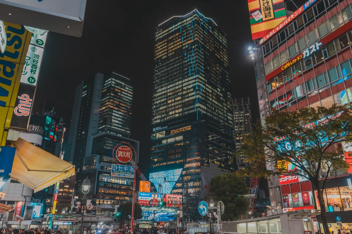 Crowds beneath glowing neon signs on a Shinjuku street at night