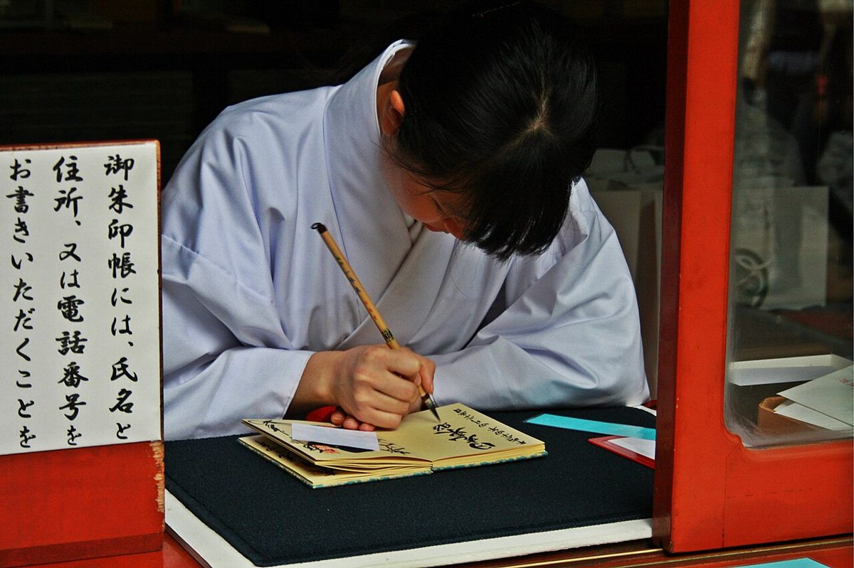 A brush writing Japanese characters in black ink during a shodo calligraphy session