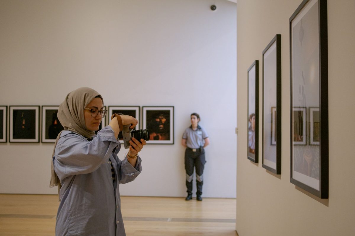 A visitor photographing a luminous digital installation on a phone