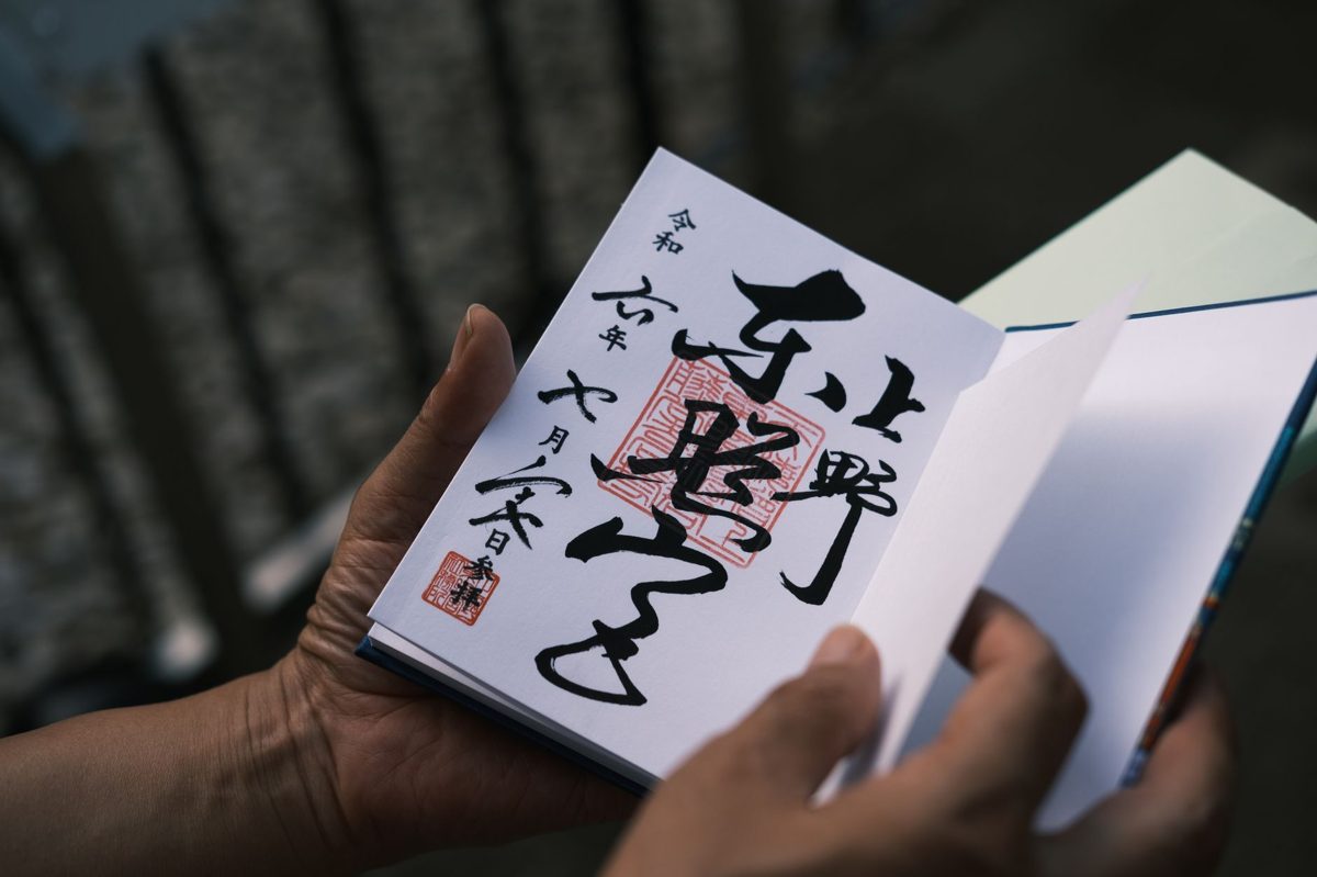 A hand-brushed goshuin stamp with red seals in a Japanese stamp book