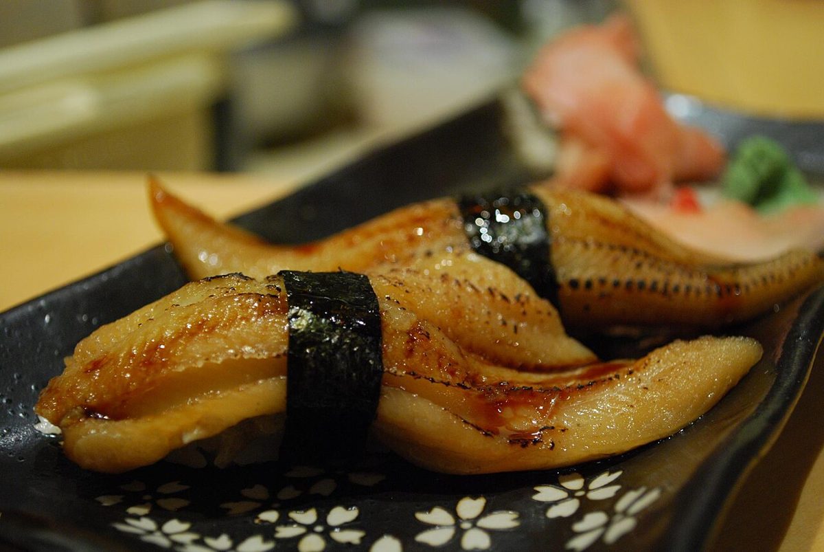 Chef preparing sushi behind a wooden counter at an omakase restaurant