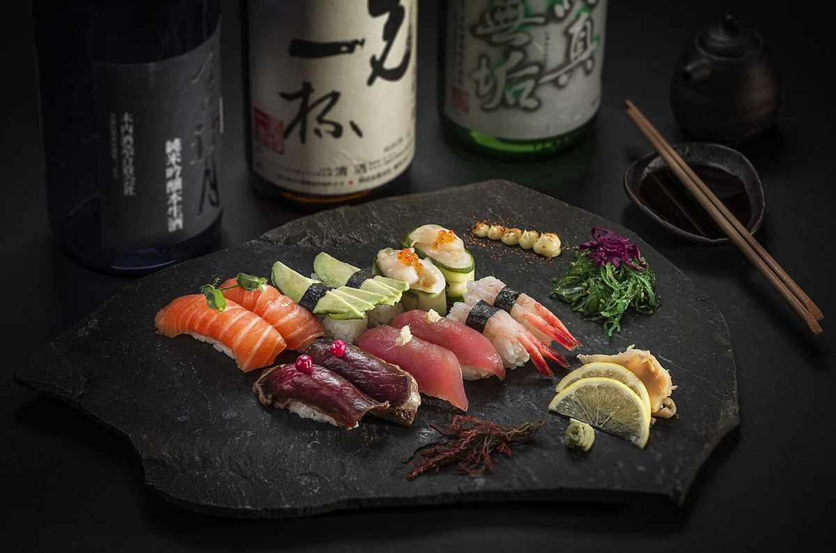 A sushi chef presenting a piece of nigiri across the counter