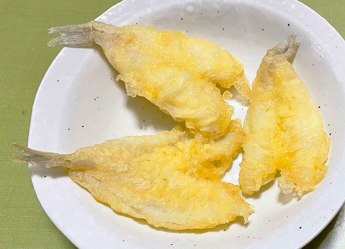 Freshly fried tempura served piece by piece at a counter