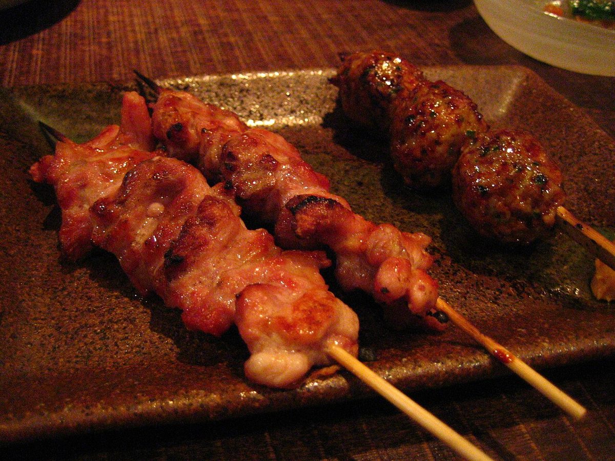 Grilled chicken meatball tsukune skewers served with a dipping sauce