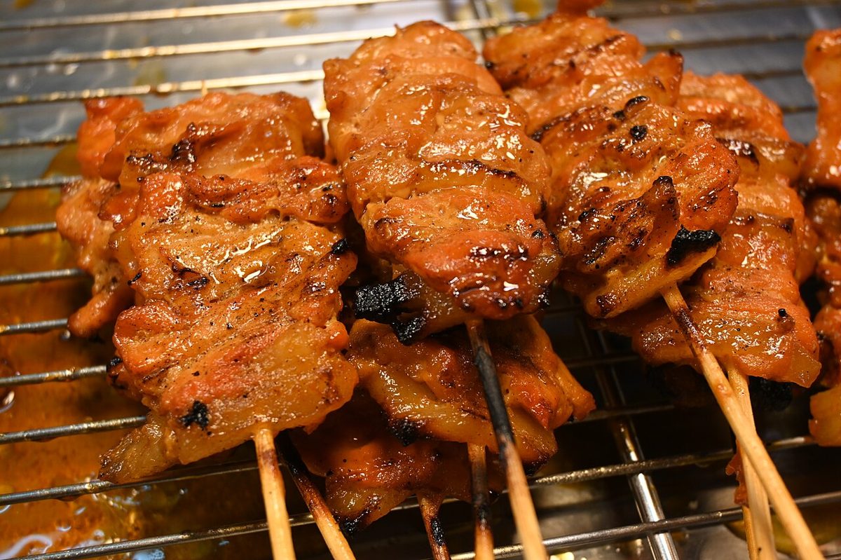 Skewers of chicken grilling over charcoal at a yakitori stall