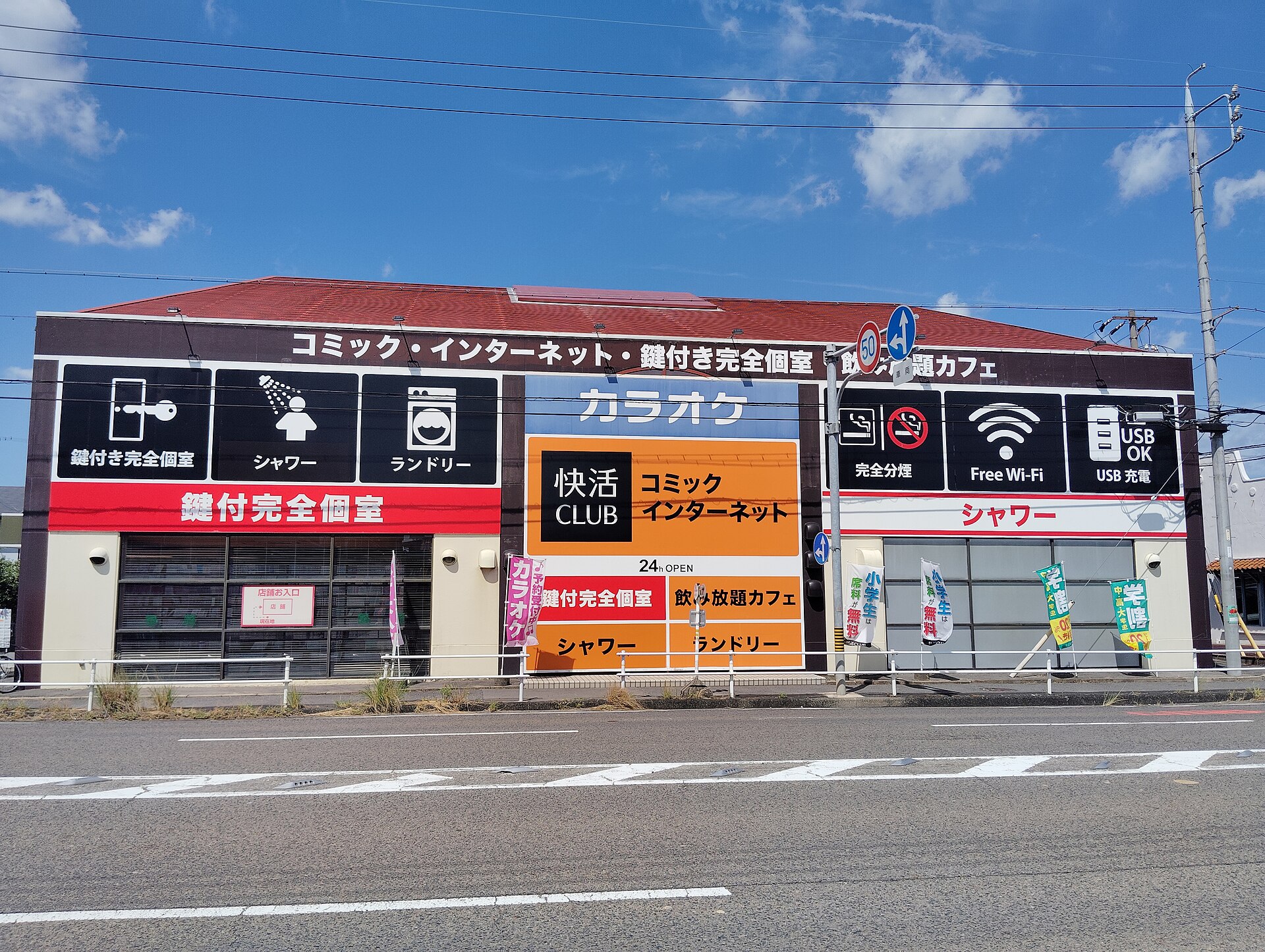 The exterior of a Kaikatsu Club manga and internet cafe with signs for private rooms, showers, laundry and free wifi