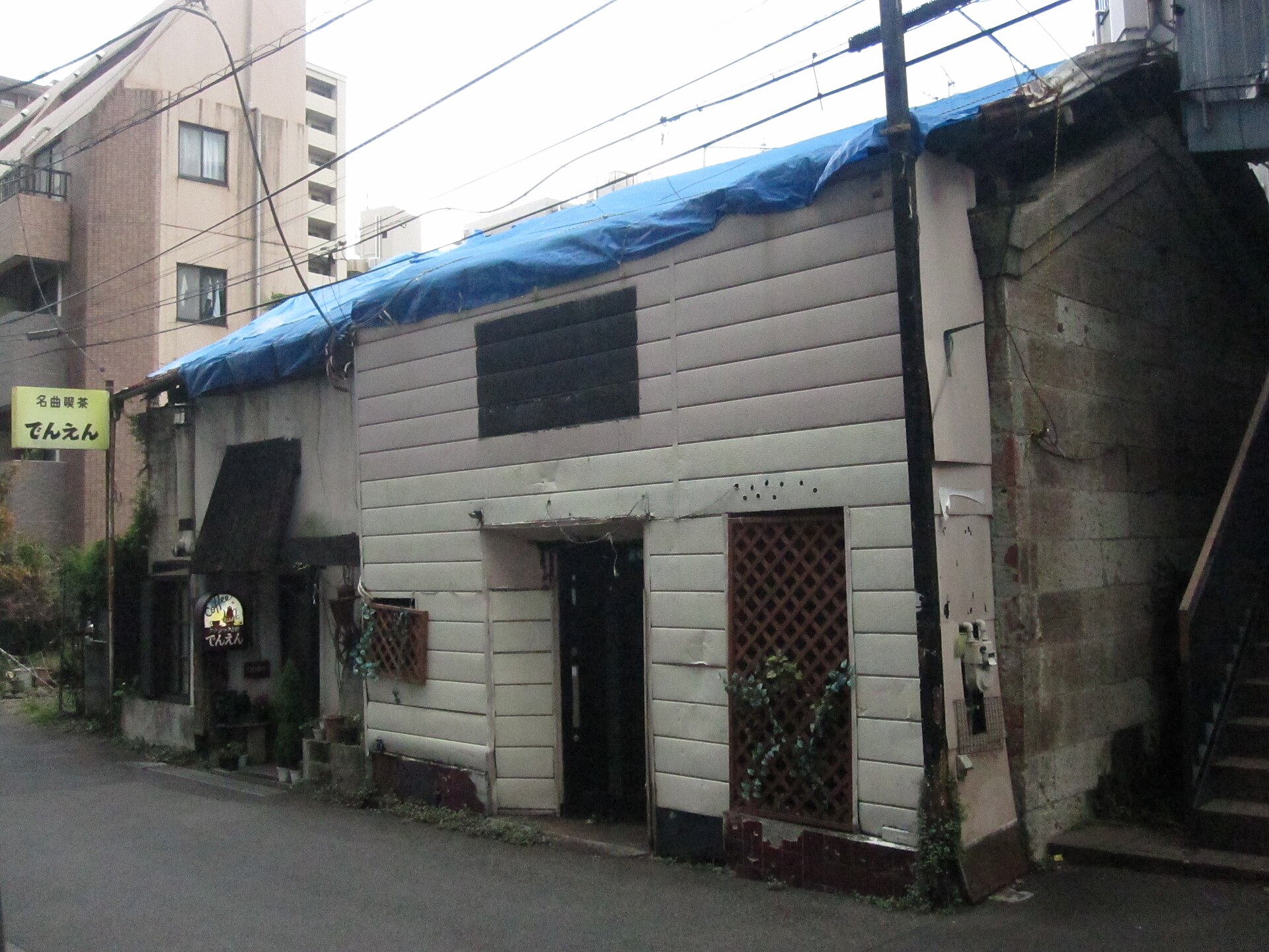 A weathered wooden building with a small yellow classical-music coffee house sign