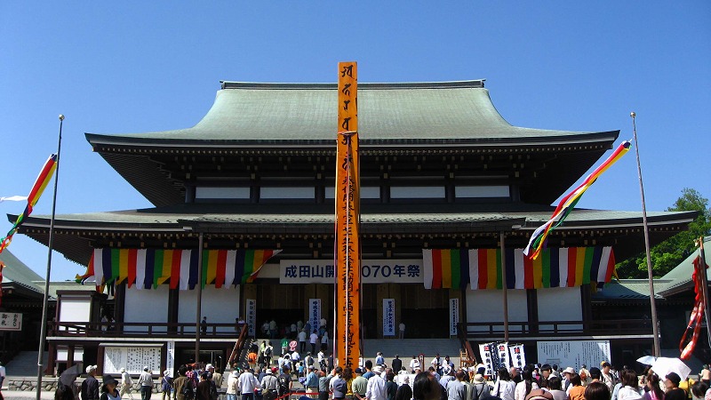 The large main hall of Naritasan Shinshoji temple with festival banners and crowds in front
