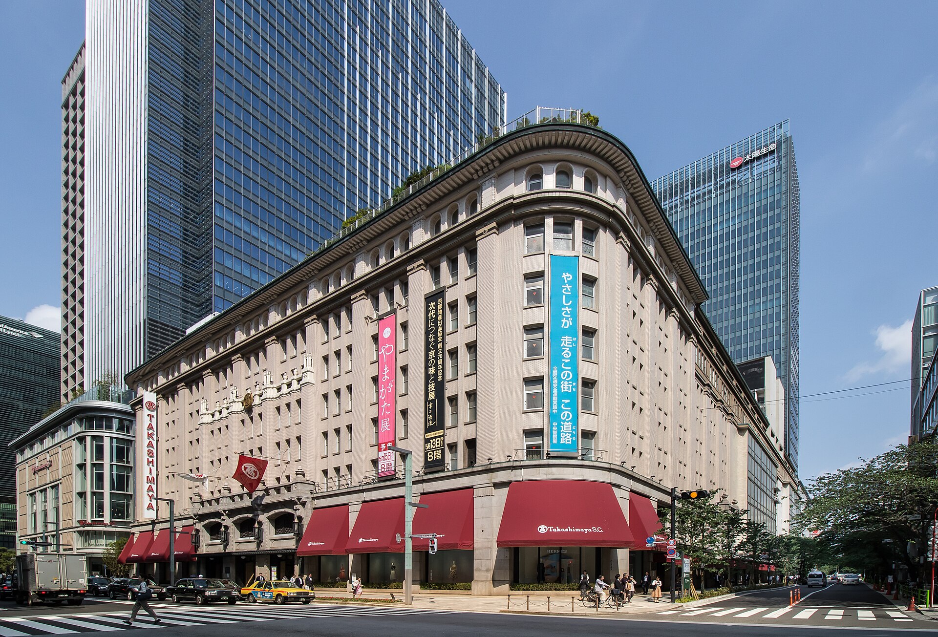 The historic stone facade of Takashimaya department store in Nihonbashi with red awnings and modern towers behind