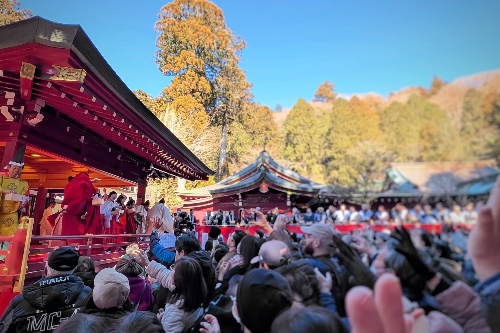 Priests throwing roasted beans from a shrine platform into a crowd with raised hands