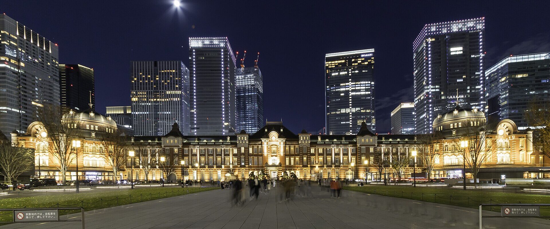 The red-brick Tokyo Station Marunouchi building floodlit at night with bare winter trees