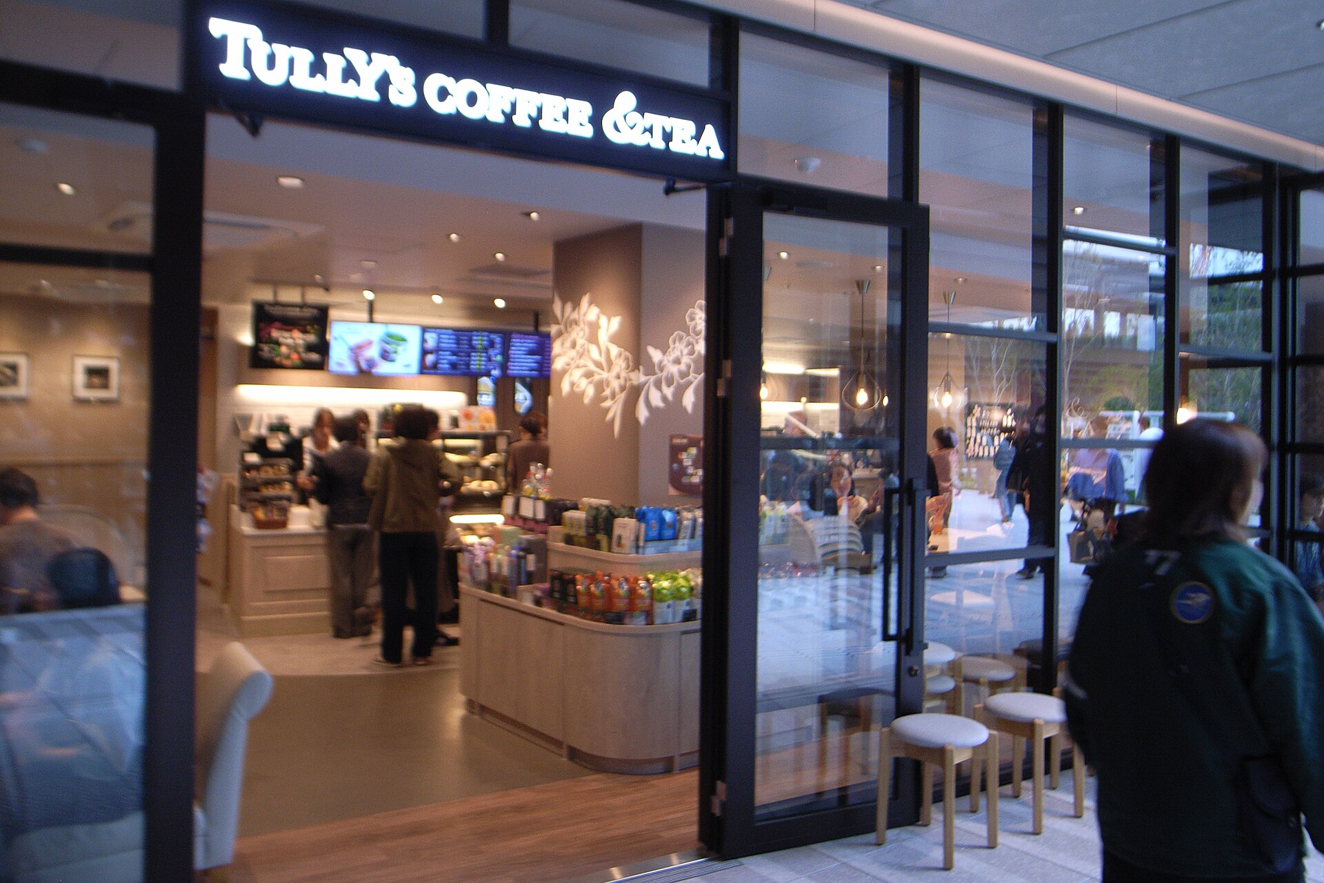 The glass entrance of a Tully's Coffee and Tea branch with a counter and shelves of coffee goods inside