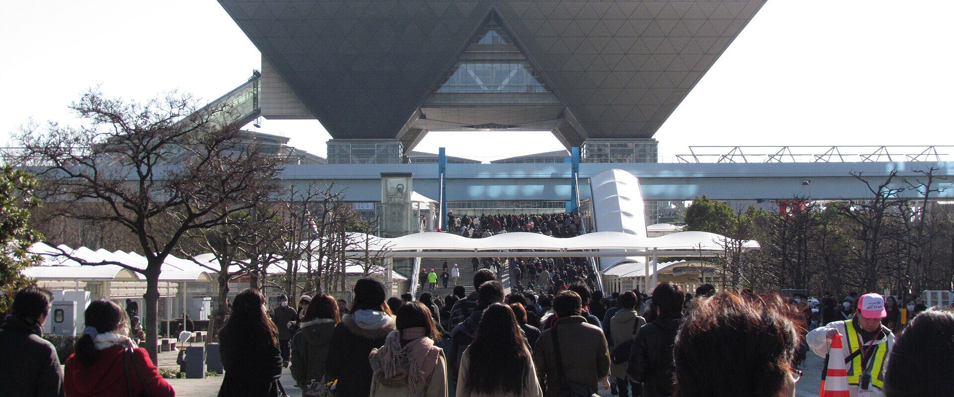 Crowds walking towards the inverted-pyramid towers of Tokyo Big Sight on a winter morning during Comic Market