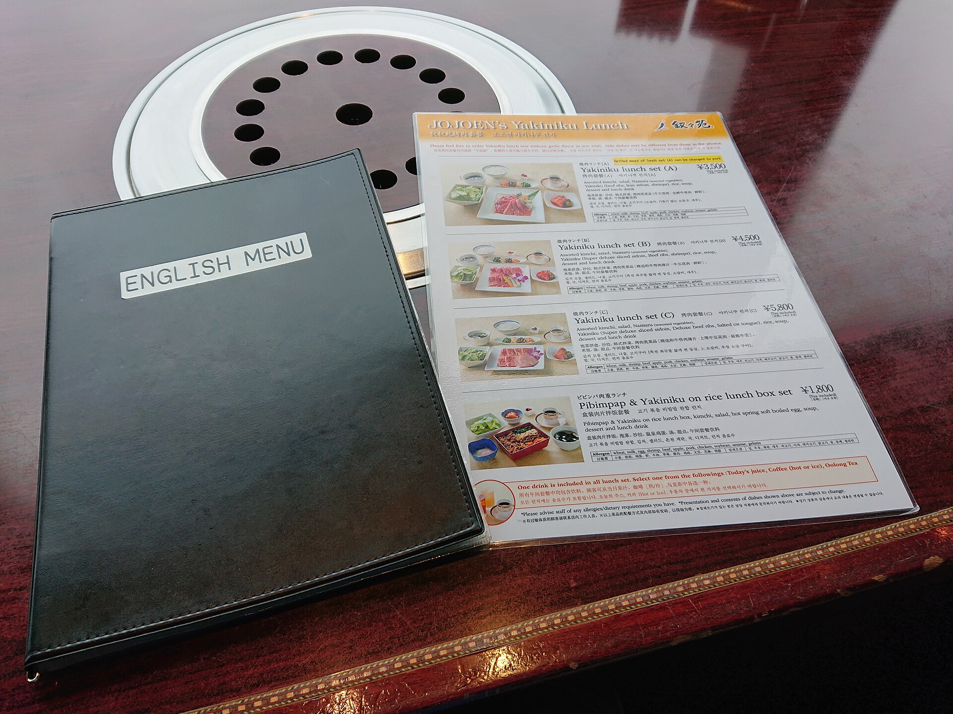An English yakiniku lunch menu at the Jojoen restaurant in Tokyo Skytree, with photos of set meals beside a round tabletop grill