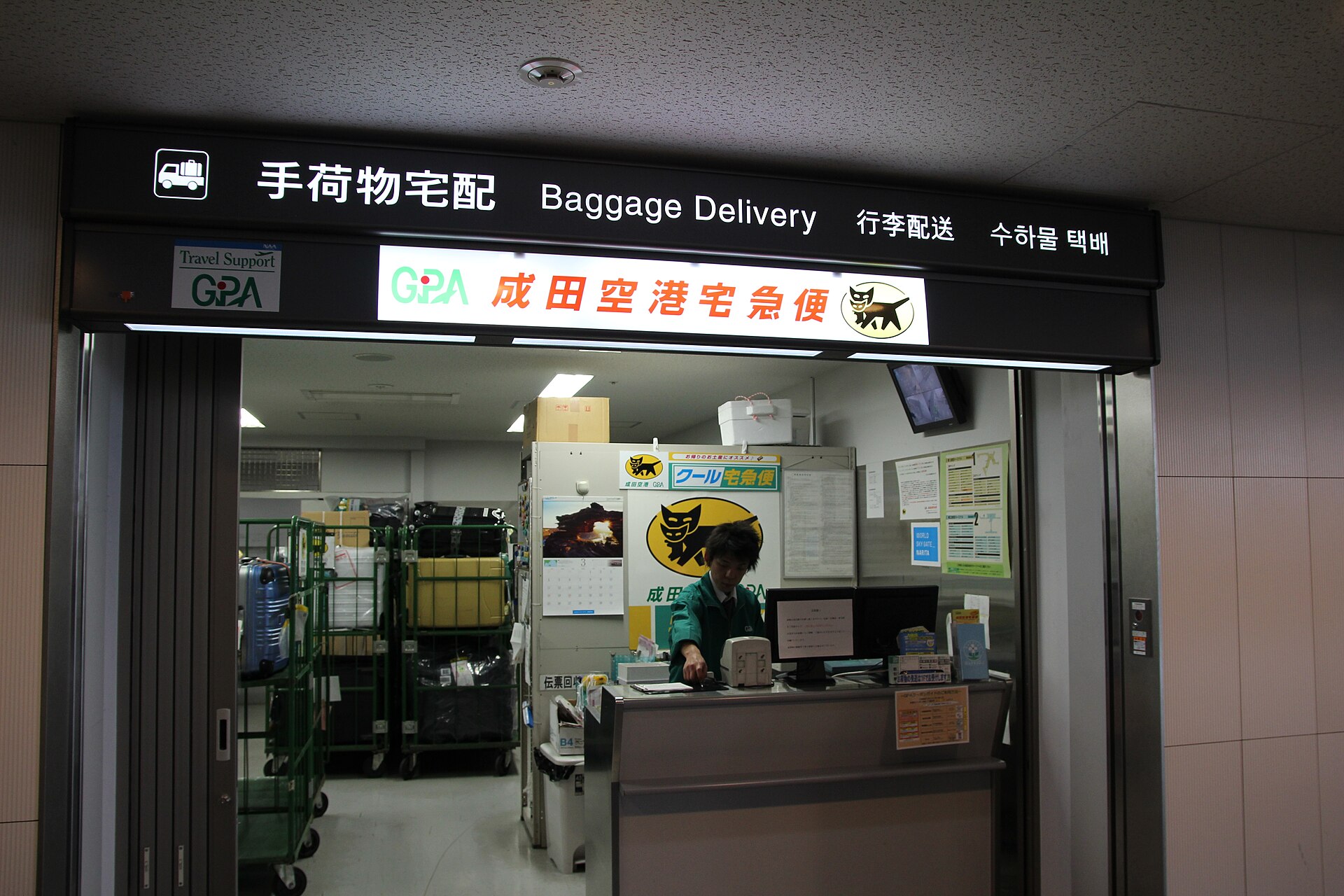 A Kuroneko Yamato baggage delivery counter at Narita Airport with suitcases on trolleys behind the desk