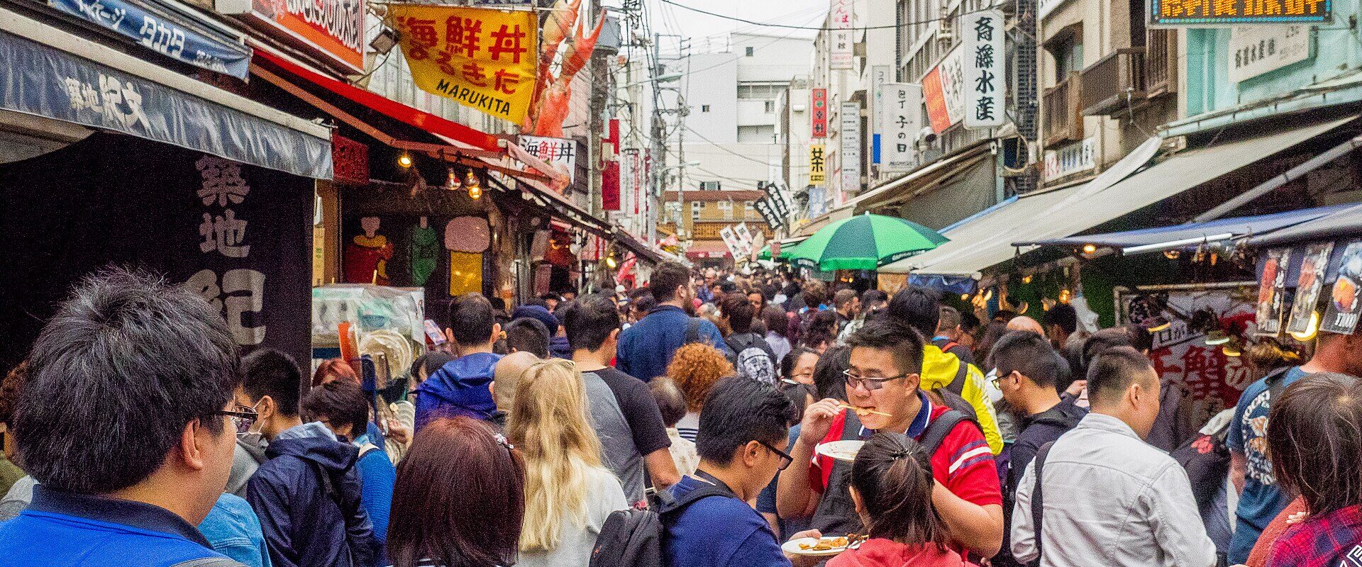 Shoppers fill a narrow lane between food stalls and seafood shops at Tsukiji Outer Market in Tokyo.
