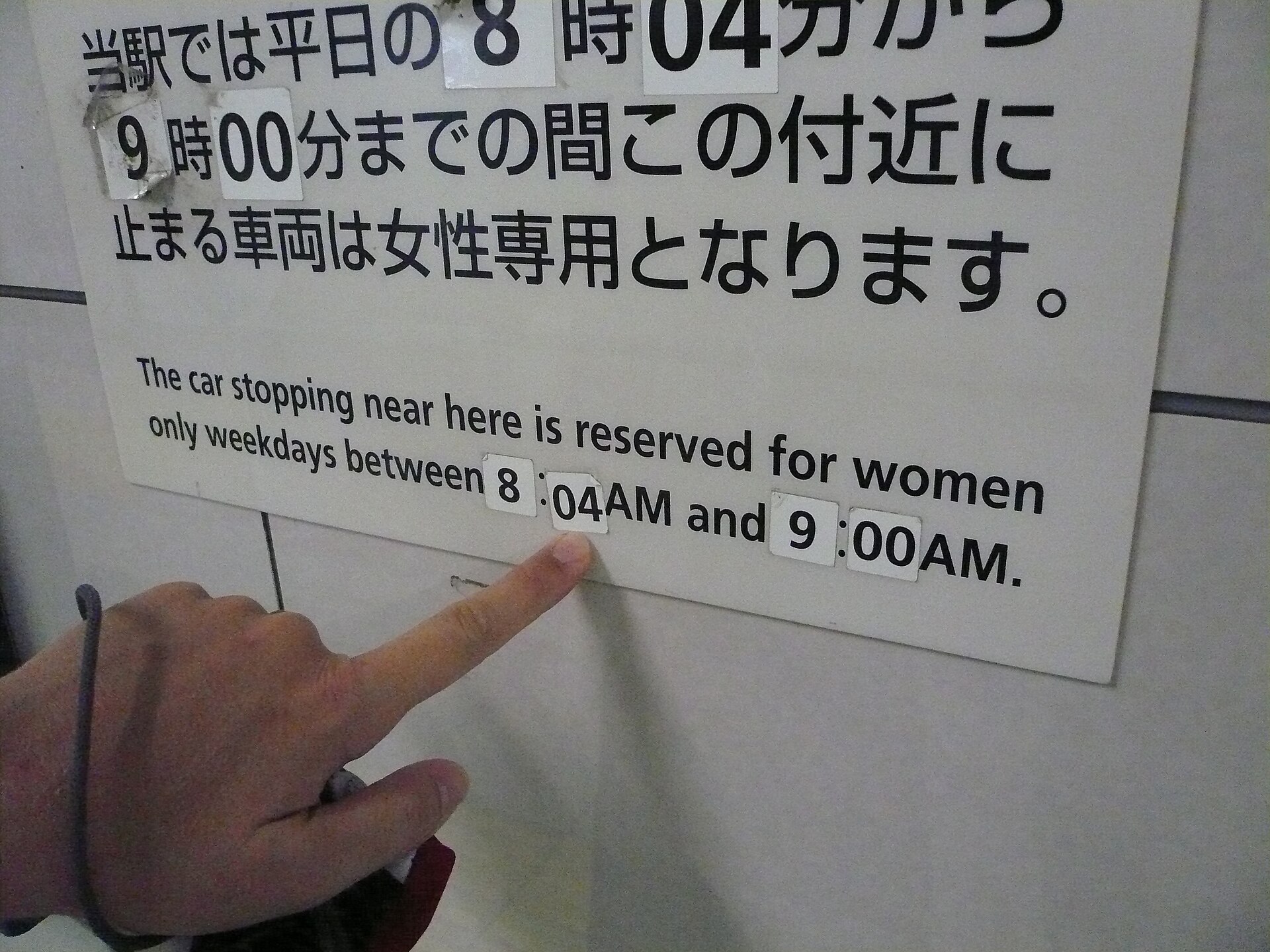 A sign on a Tokyo subway platform in Japanese and English saying the car stopping nearby is reserved for women on weekday mornings